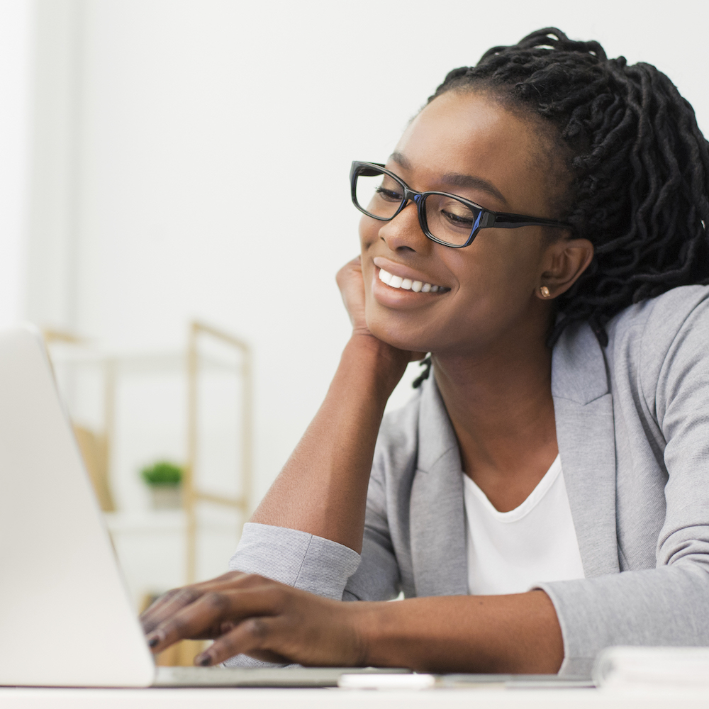 Cheerful Afro Office Girl Using Laptop At Workplace